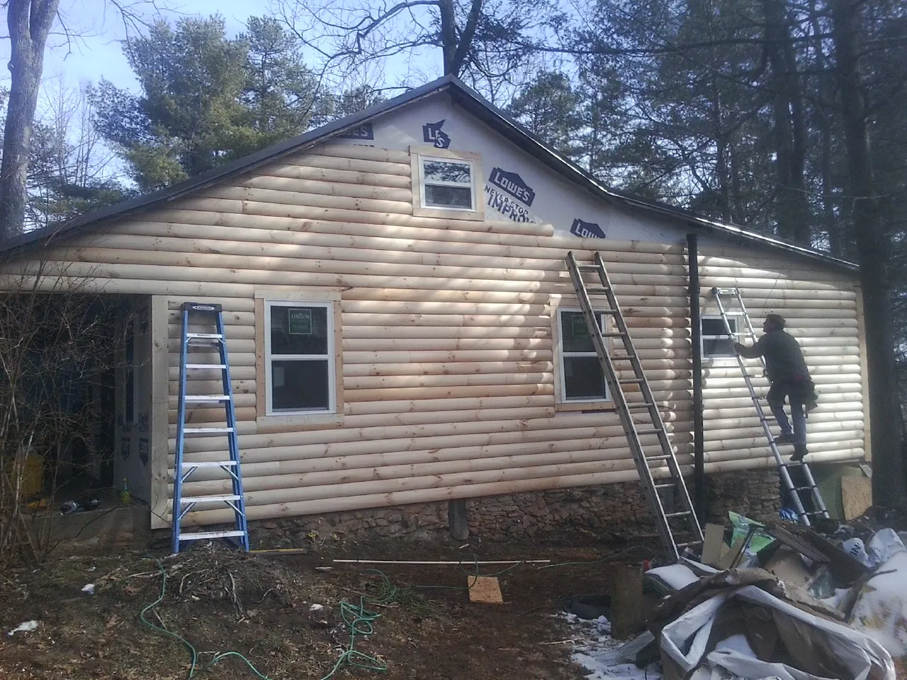 Ladders set against fresh log siding during an exterior remodel in Carrollton