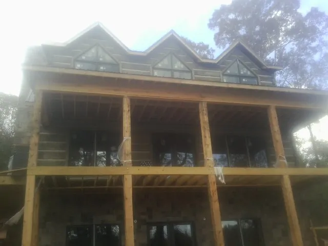Dormers and porch framing on a large log home under construction — Roof Coating work by our crew in Carrollton